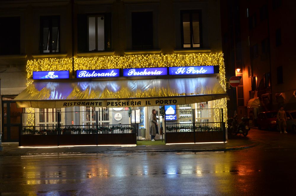 Ristorante con tenda e insegna incorniciate dalle luminarie