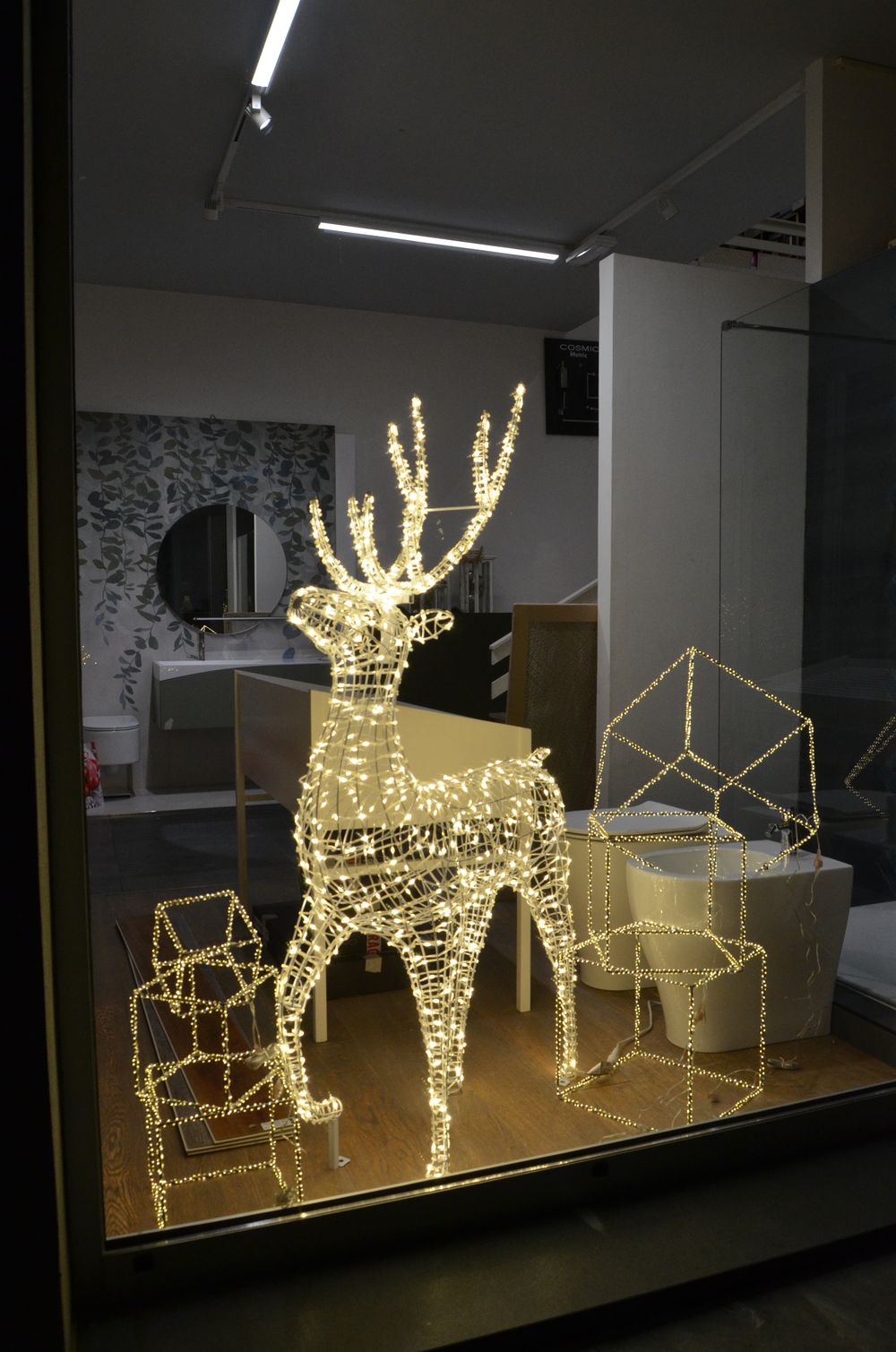 Renna luminosa e pacchi regalo nella vetrina di uno showroom